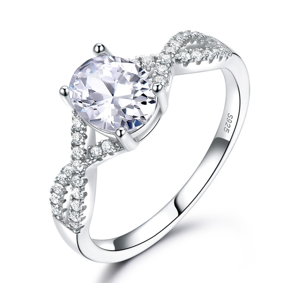 Alphalurent Infinity Azure Ring – Oval-Cut Sapphire Blue Crystal in S925 Model_s Hand Alphalurent 925 sterling silver ring featuring a vibrant oval-cut crystal center stone on a sparkling twisted infinity band, shown surrounded by white pearls. Available in blue, green, light blue, pink, and white.