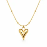 Gold Alphalurent titanium steel necklace featuring a smooth, 3D geometric heart pendant on a beaded snake chain.