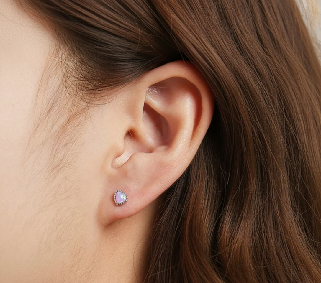 Alphalurent 925 sterling silver stud earrings featuring a heart-shaped iridescent blue opal crystal, a beaded silver edge, and comfortable screw-on ball backs.