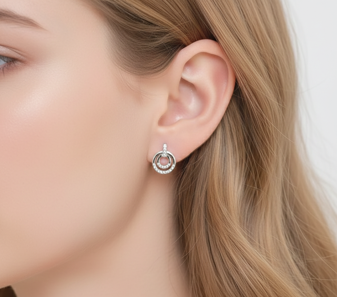 Alphalurent 925 sterling silver stud earrings featuring a geometric design with two interlocking circles, accented with sparkling pave crystals.