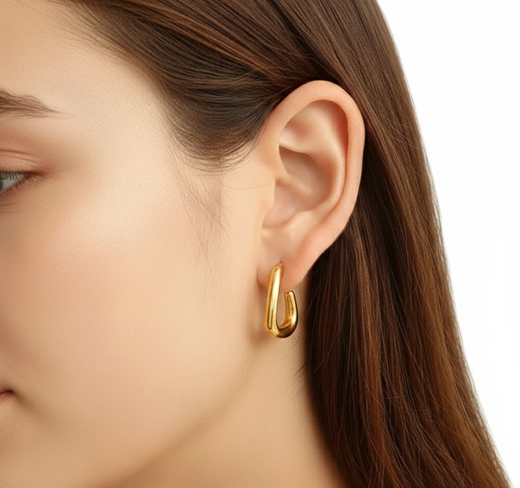Alphalurent gold titanium steel hoop earrings featuring an irregular, fluid U-shape geometric design. (For the silver image): Model wearing Alphalurent asymmetric silver U-shaped hoop earrings with a sleek, modern finish.