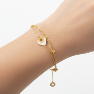 Alphalurent gold titanium steel bracelet featuring a double-strand chain with small tube beads and a white shell heart charm.
