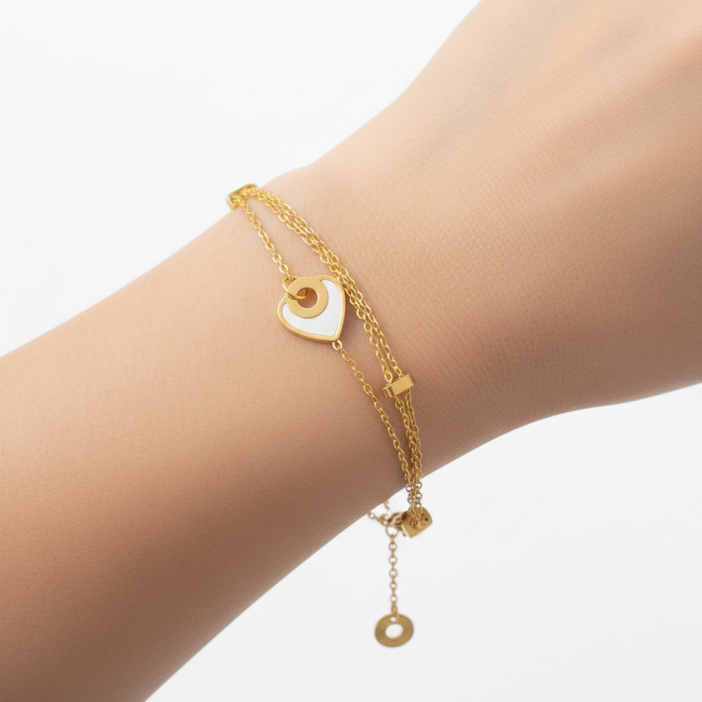 Alphalurent gold titanium steel bracelet featuring a double-strand chain with small tube beads and a white shell heart charm.