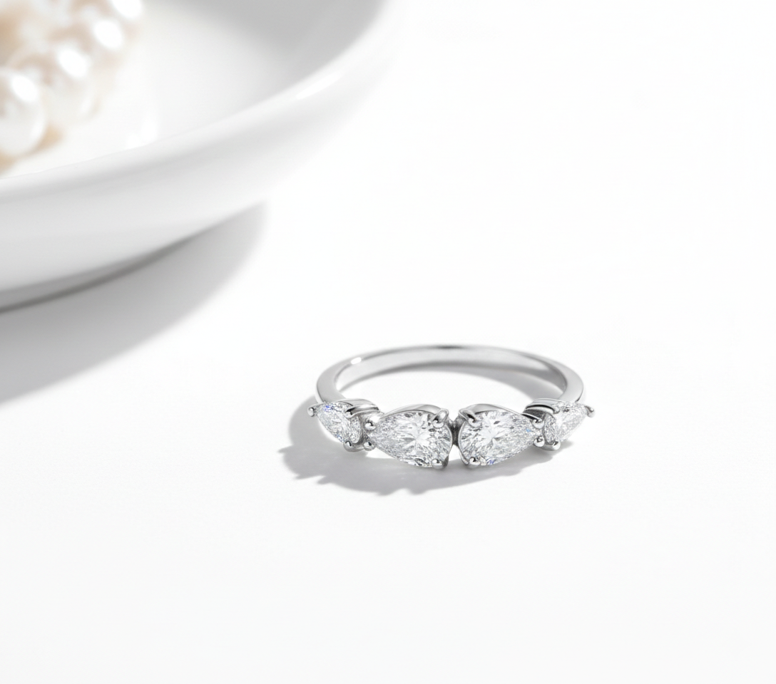 Alphalurent 925 sterling silver ring featuring five sparkling pear-cut cubic zirconia stones arranged in a row. (For the model images): Model wearing a delicate Alphalurent 925 silver 5-stone teardrop crystal ring.