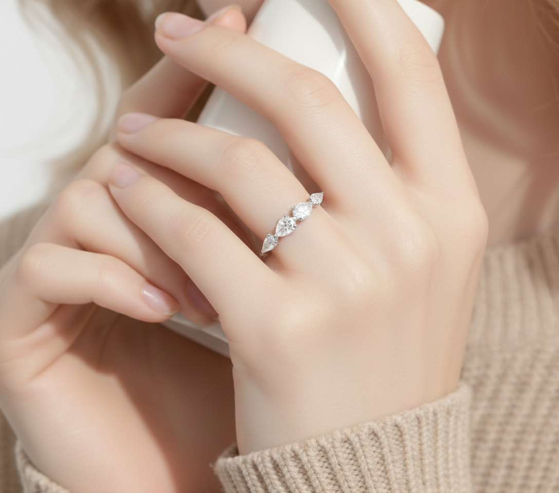 Alphalurent 925 sterling silver ring featuring five sparkling pear-cut cubic zirconia stones arranged in a row. (For the model images): Model wearing a delicate Alphalurent 925 silver 5-stone teardrop crystal ring.