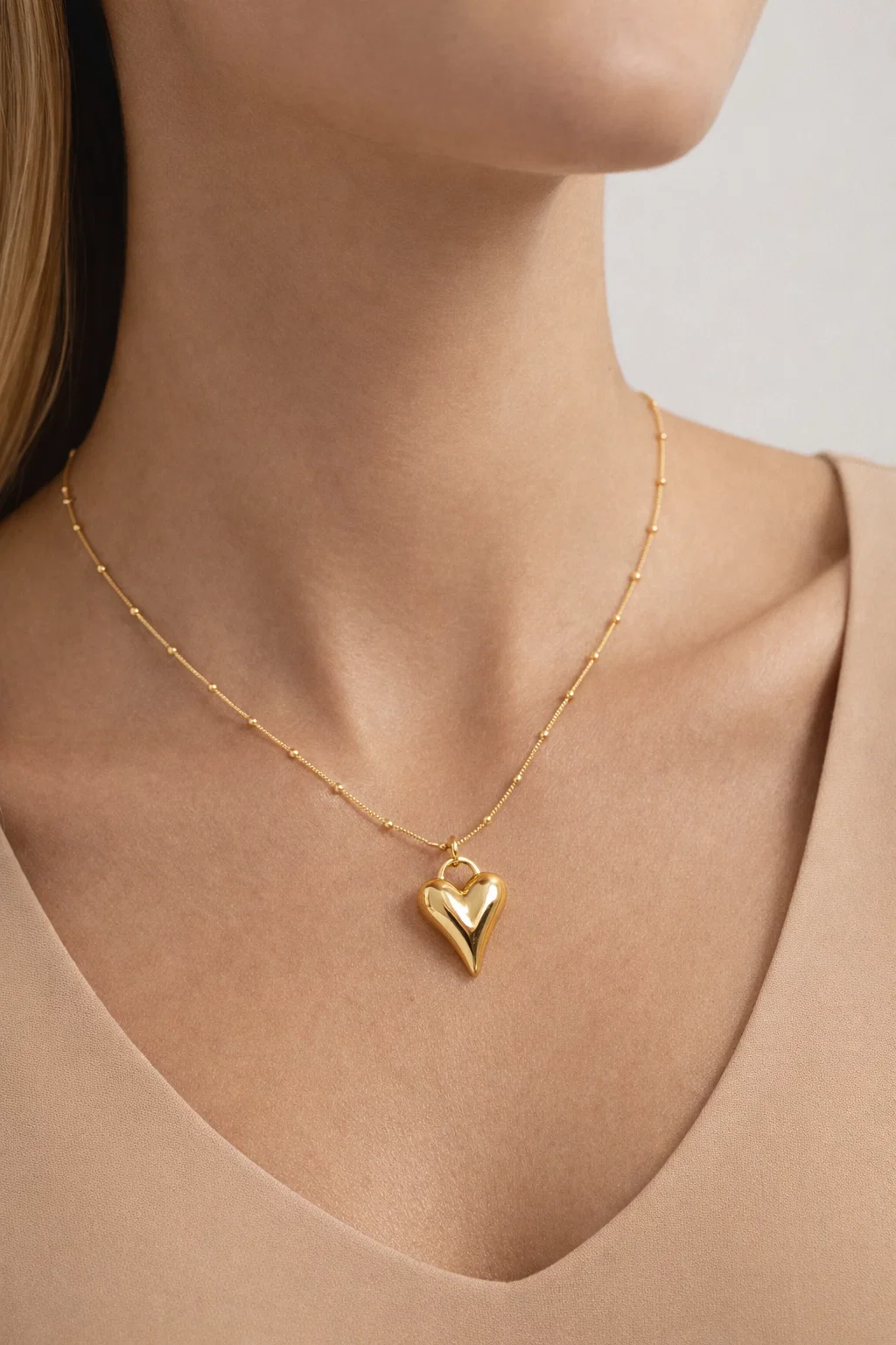 Gold Alphalurent titanium steel necklace featuring a smooth, 3D geometric heart pendant on a beaded snake chain.