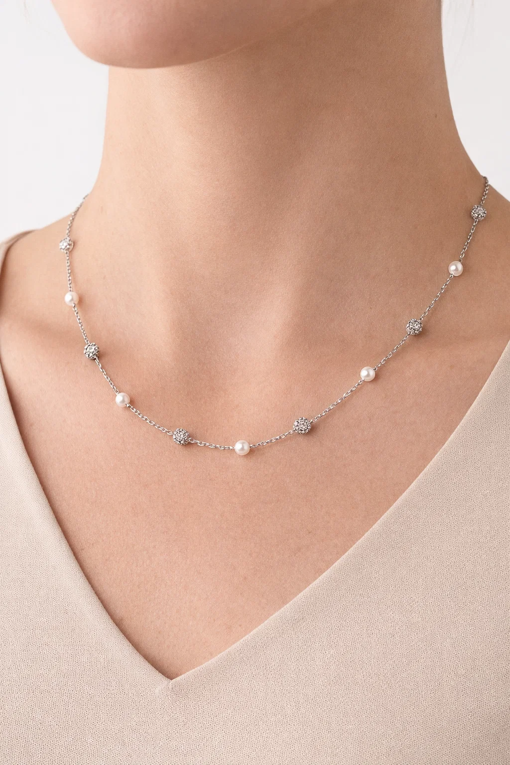 Model wearing an Alphalurent silver chain necklace featuring alternating white shell pearls and textured silver beads.