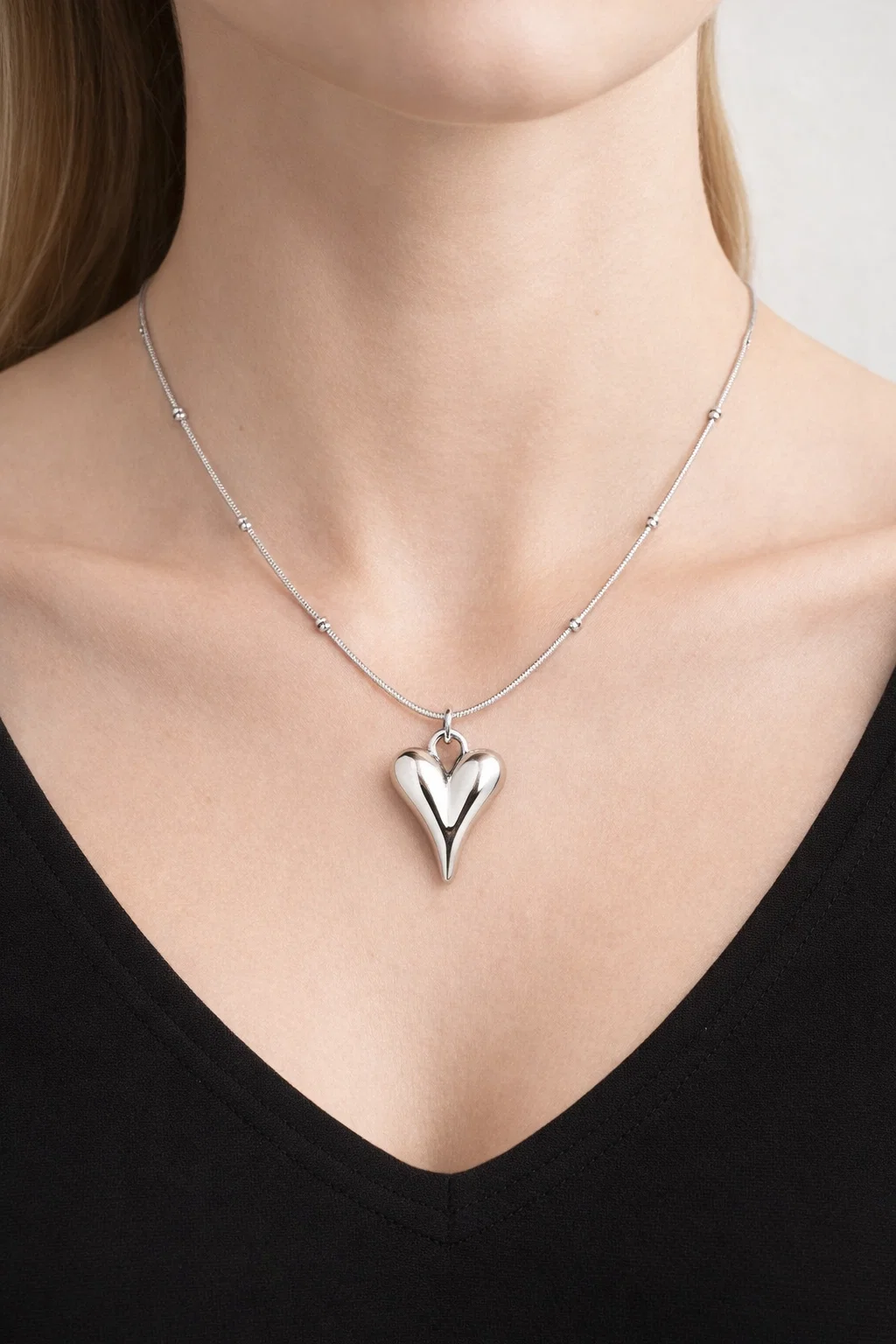 Gold Alphalurent titanium steel necklace featuring a smooth, 3D geometric heart pendant on a beaded snake chain.
