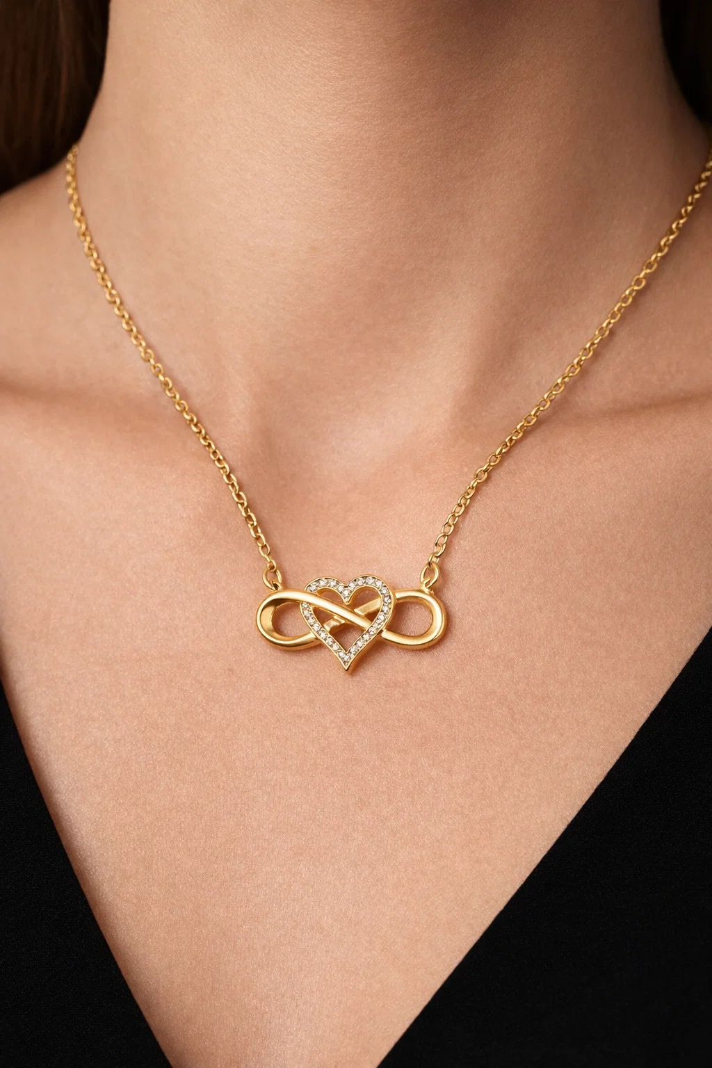 Infinity Lume gold plated necklace with infinity heart pendant and zircon center on velvet background